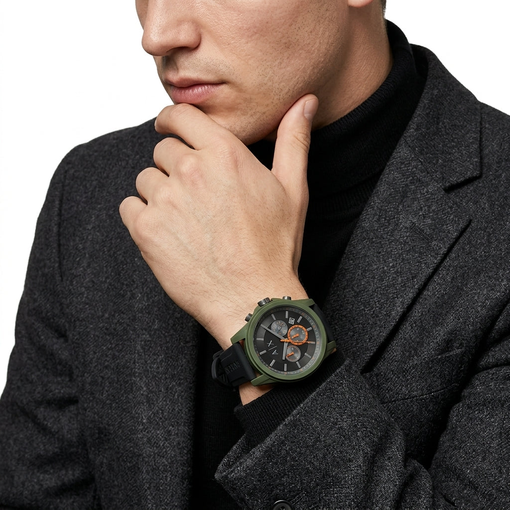 A close-up of a man wearing a dark gray blazer and black turtleneck, showcasing a rugged green analog watch with a black strap and orange accents on his wrist.