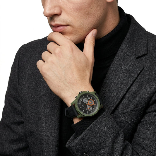 A close-up of a man wearing a dark gray blazer and black turtleneck, showcasing a rugged green analog watch with a black strap and orange accents on his wrist.