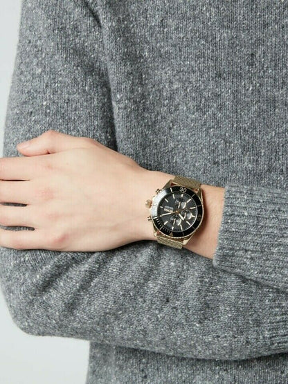 Hugo Boss watch with black dial and gold mesh strap on wrist over gray sweater